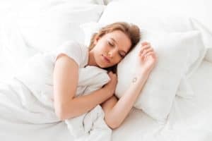 Sleeping Young Woman Lies In Bed With Eyes Closed